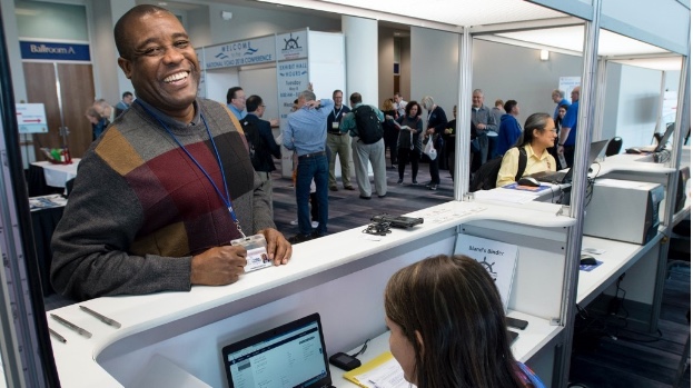 man is registering for a conference at a desk